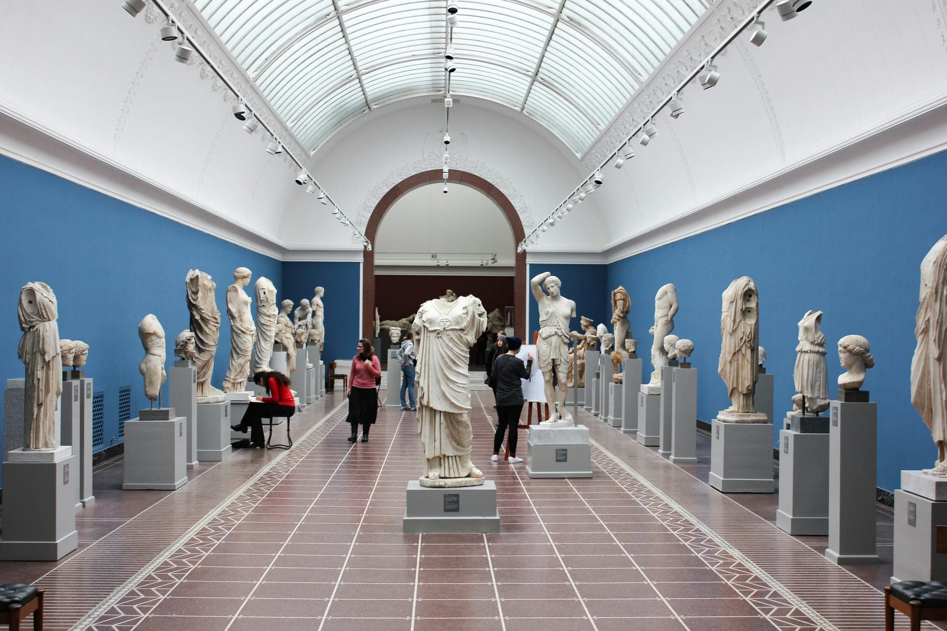Museum gallery hall with classical statues and arched columns